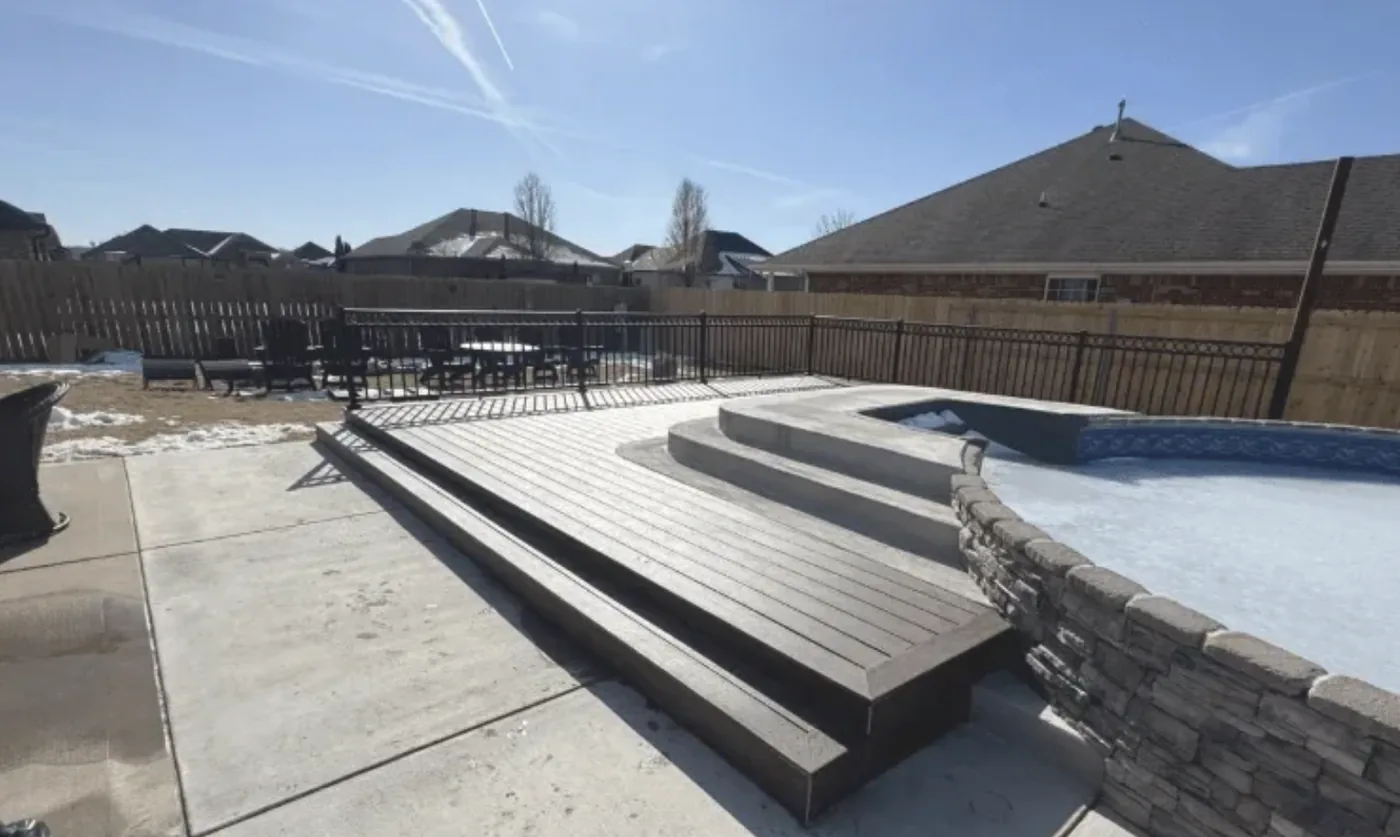 Multi-level deck beside an inground pool with stacked-stone retaining wall